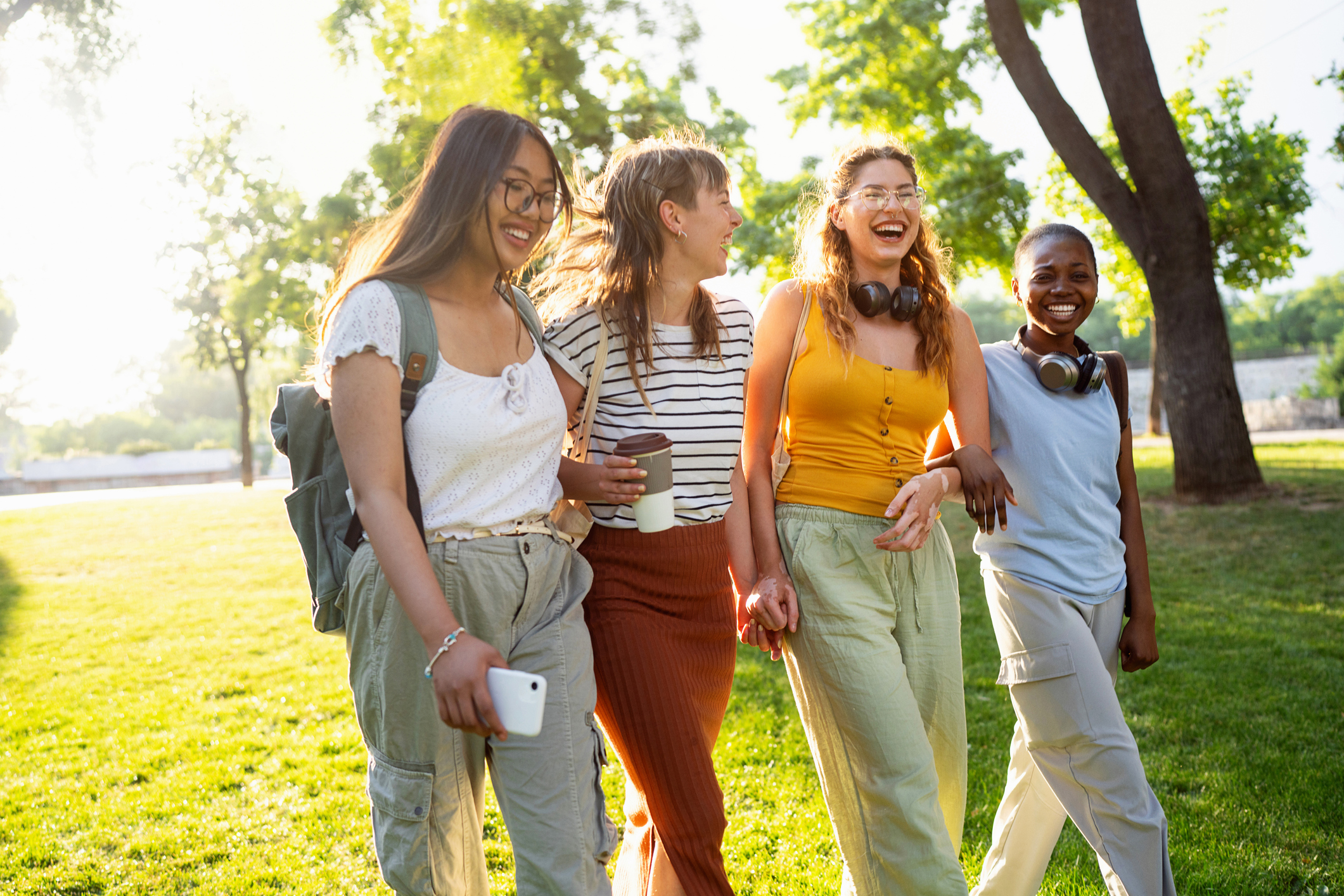 Group of modern young multiracial female friends, an University students, walking through the campus park