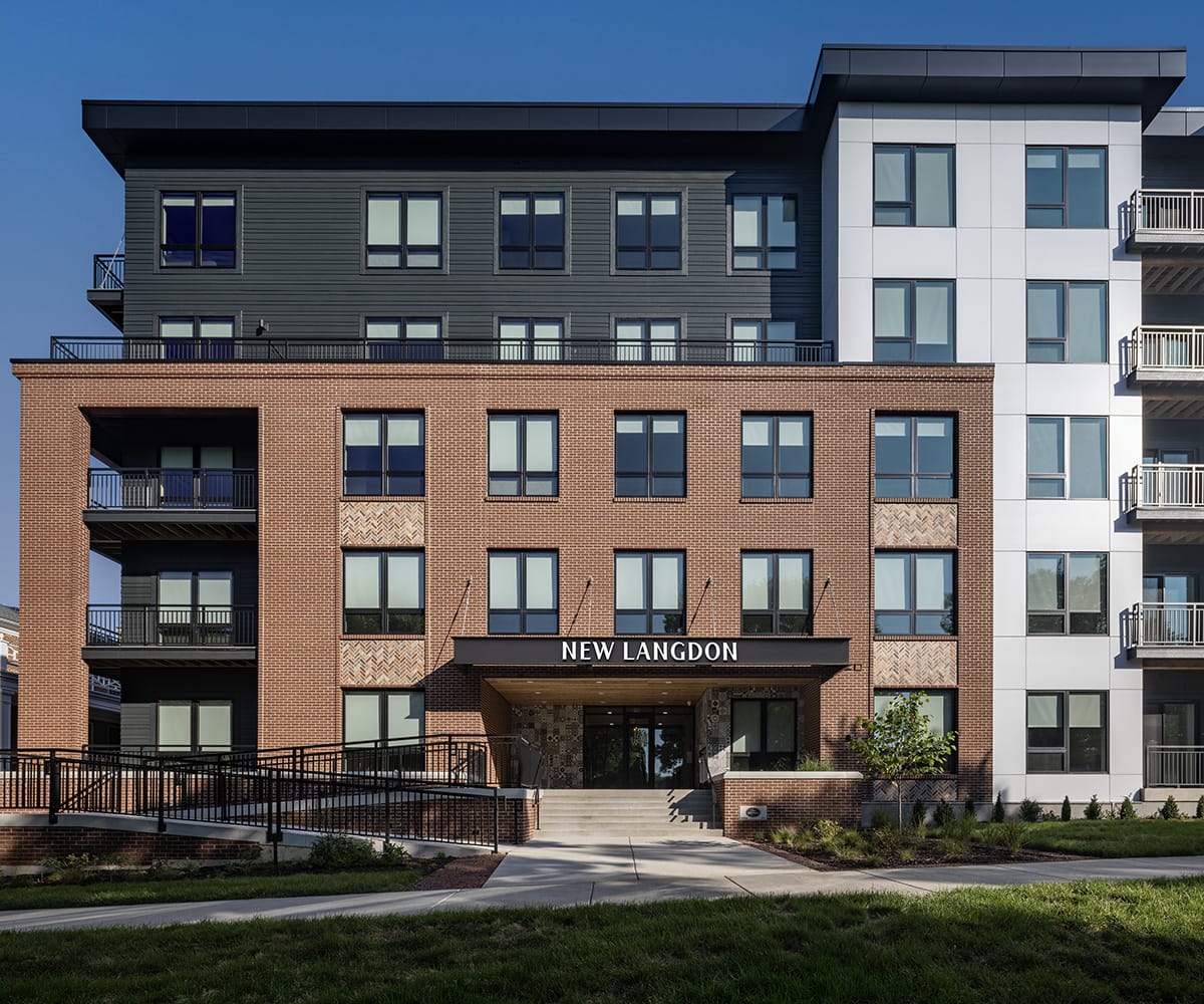 Modern apartment building with brick and white facade, balconies, and "New Langdon" sign.
